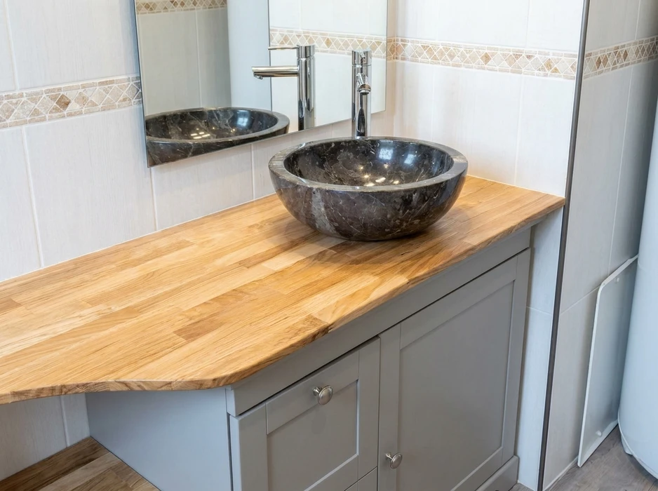 Salle de bain moderne avec vasque ronde en marbre emperador foncé, posée sur un plan de travail en chêne massif lamellé-collé