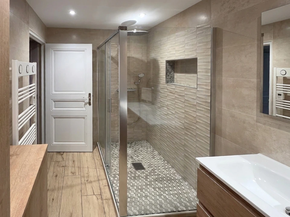 Salle de bain moderne et spacieuse avec baignoire îlot blanche autoportante, vasque à poser sur meuble console en teck, robinetterie chromée col de cygne, miroir LED encastré